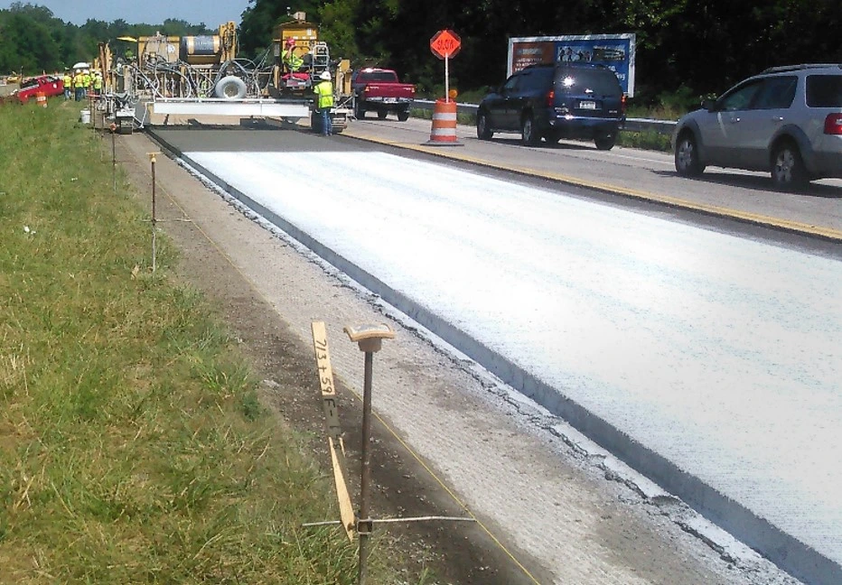 An image of construction workers applying a pavement overlay to a roadway.